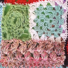 Top right: a complete half-size granny square in thin blue and white yarn. Top left: the start of a granny square in chunky green yarn. Bottom: rows of popcorn stitch in variegated pink and brown yang