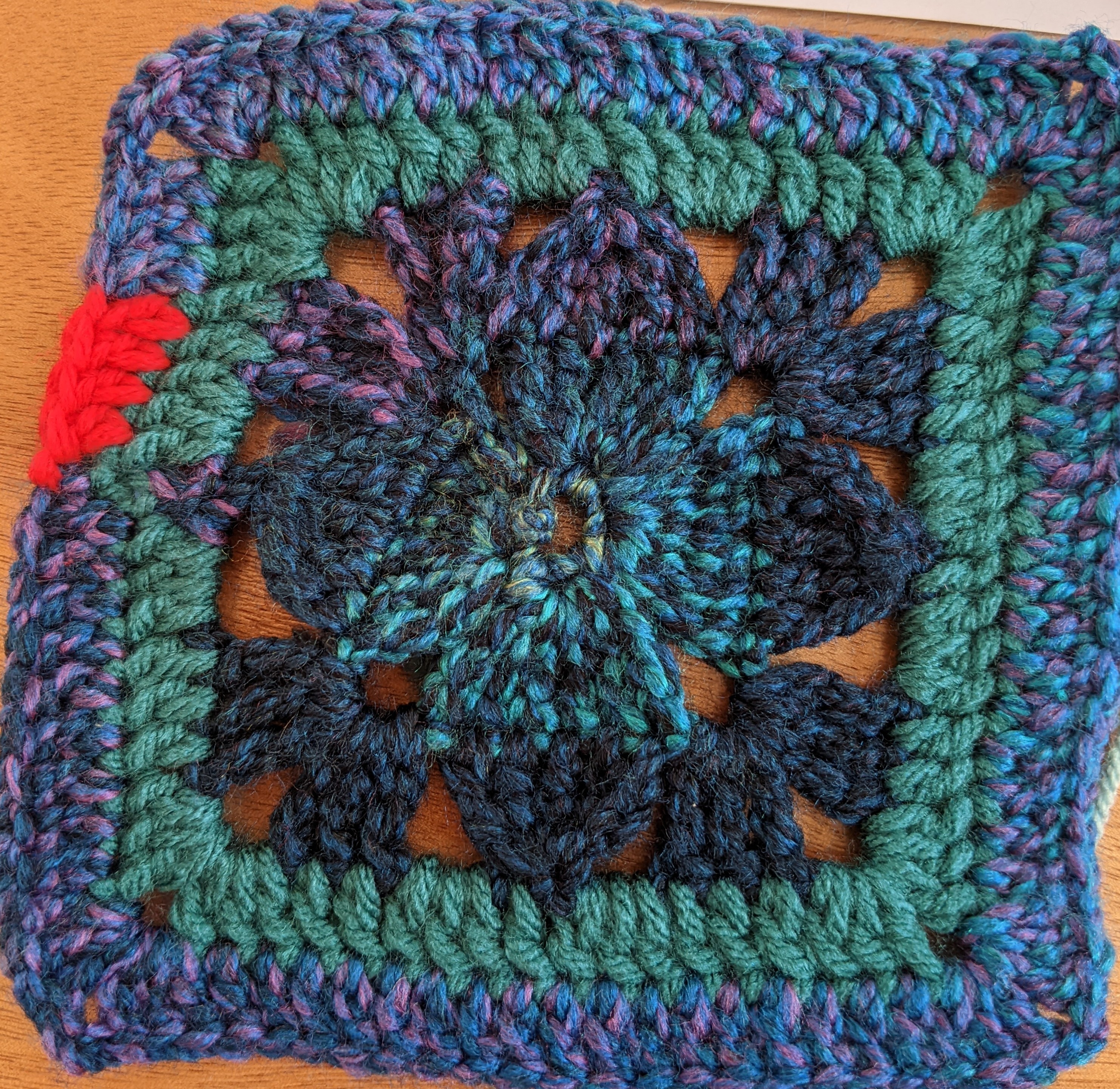 Teal granny square with a bright red dot