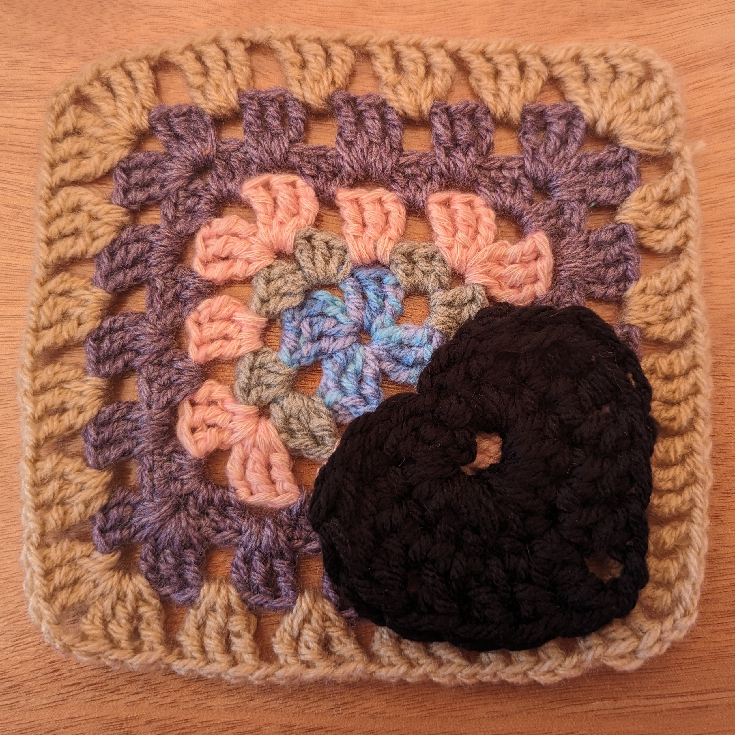 Traditional granny square in neutral tones with a black heart tied on