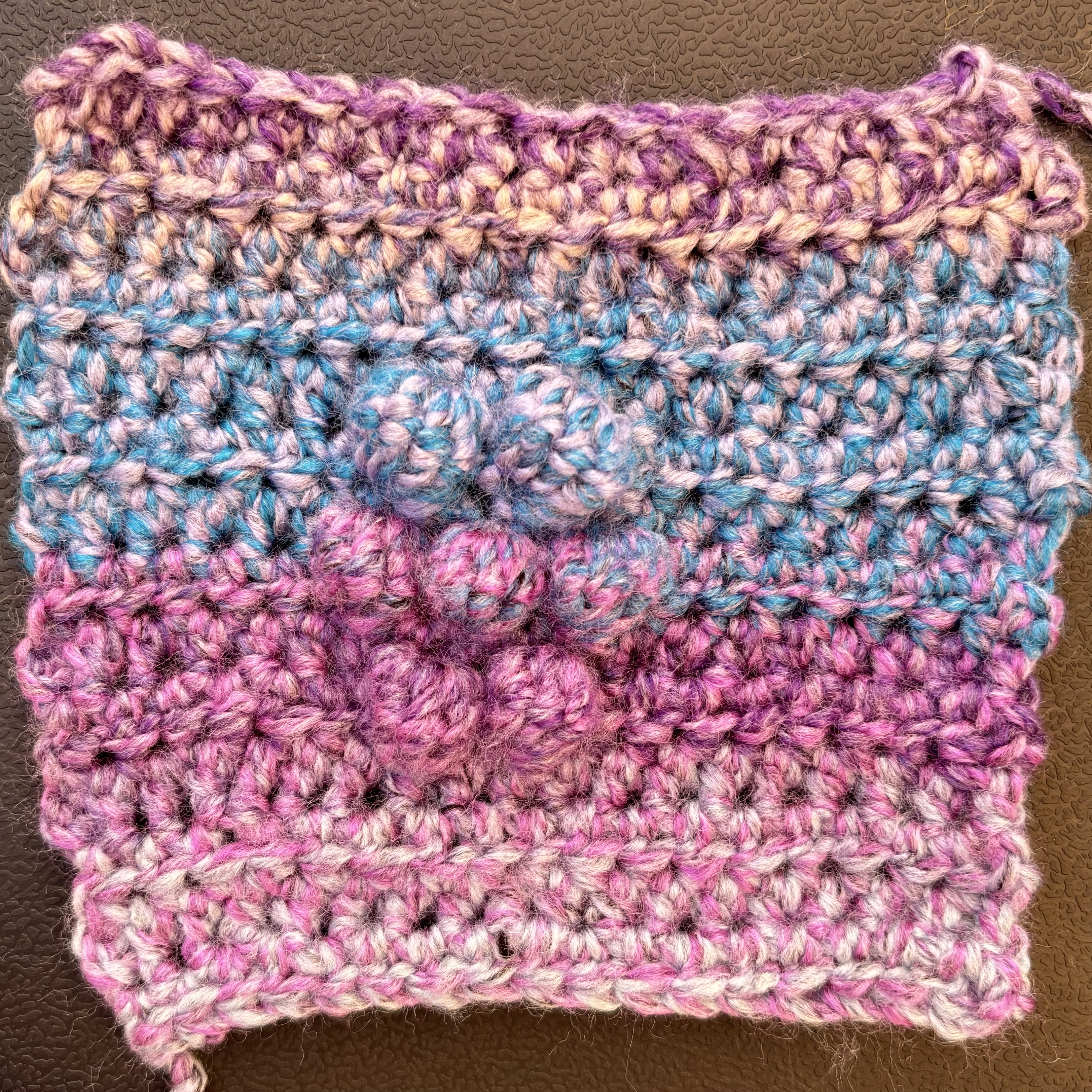 Blue and purple variegated square with bobbles in the shape of a flower
